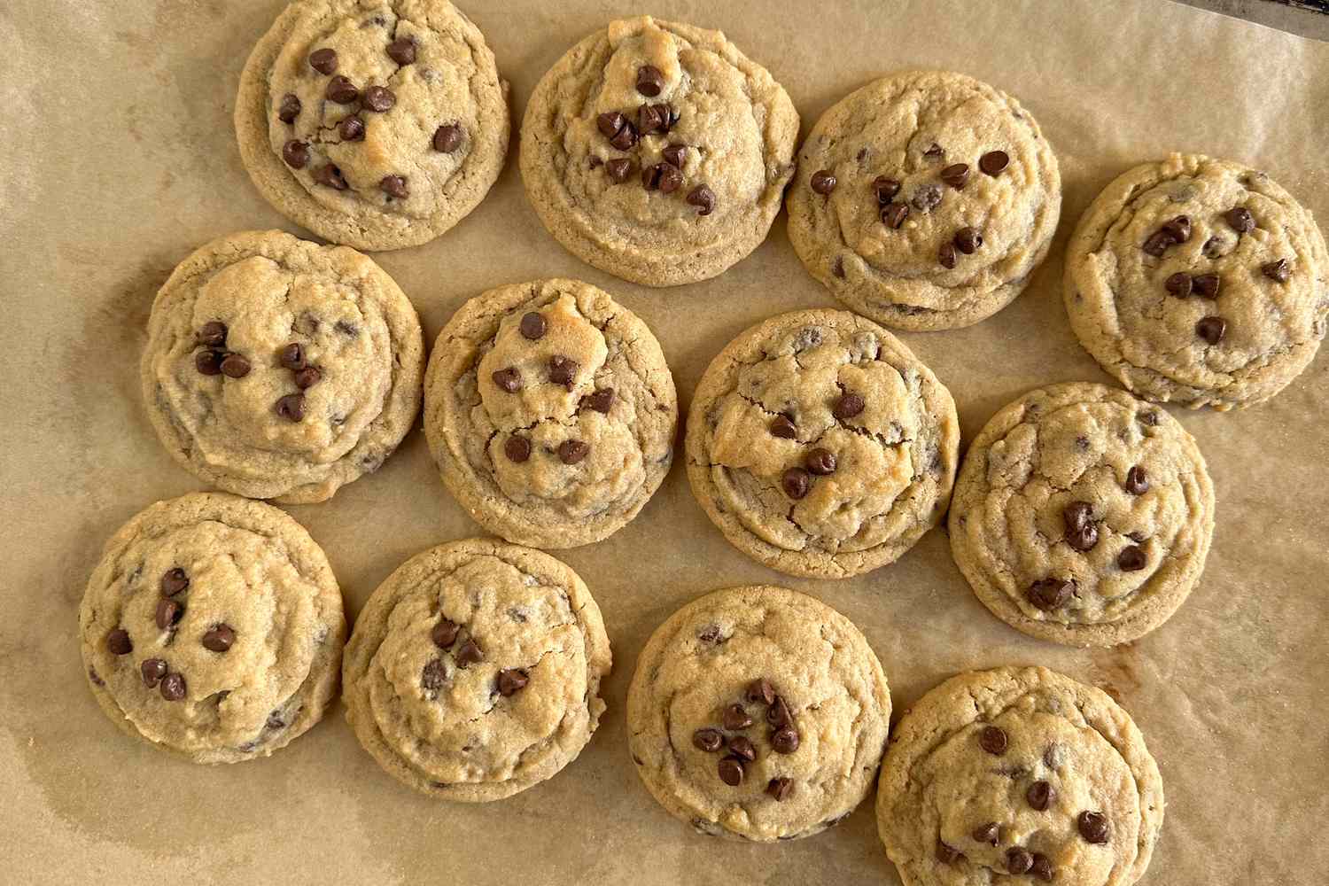 Overhead view of a baking sheet of chocolate chip cookies on parchment paper
