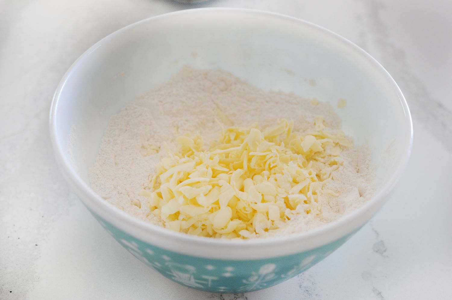 Dry ingredients and grated butter in a bowl to make a Basic Scone Recipe.