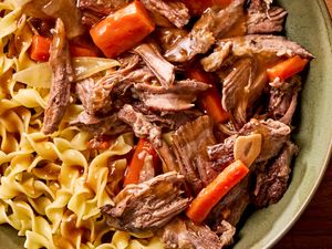 Pot roast with carrots and egg noodles served on a plate