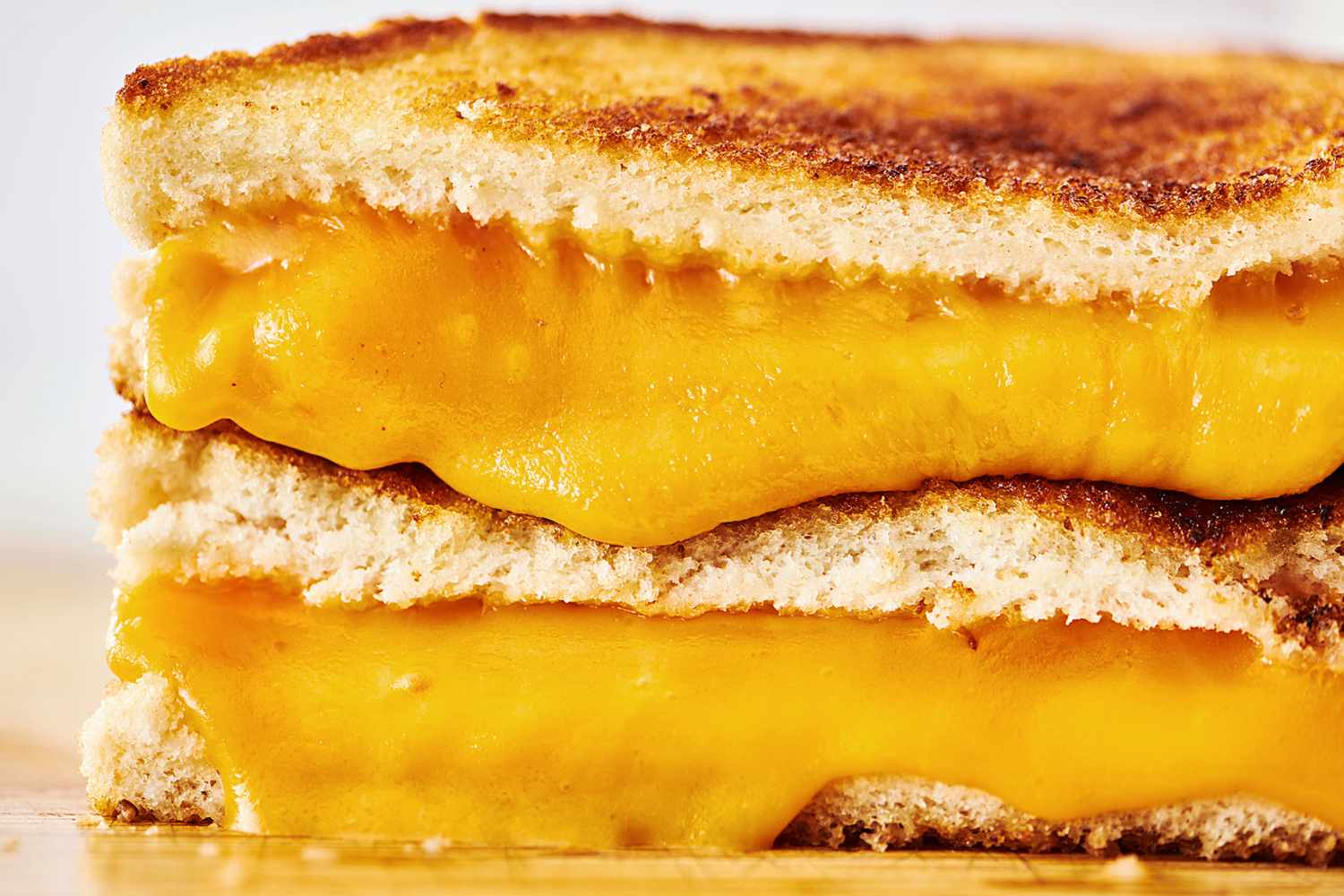 A closeup of a grilled cheese sandwich with melted cheese oozing between slices of toasted bread