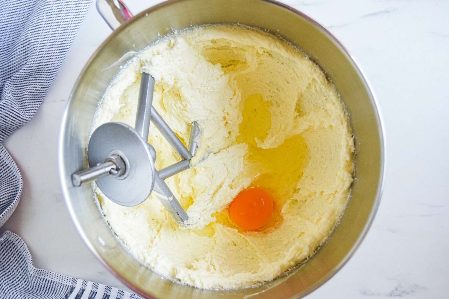 Creamed butter and sugar and an egg in a mixing bowl for a chocolate cake recipe
