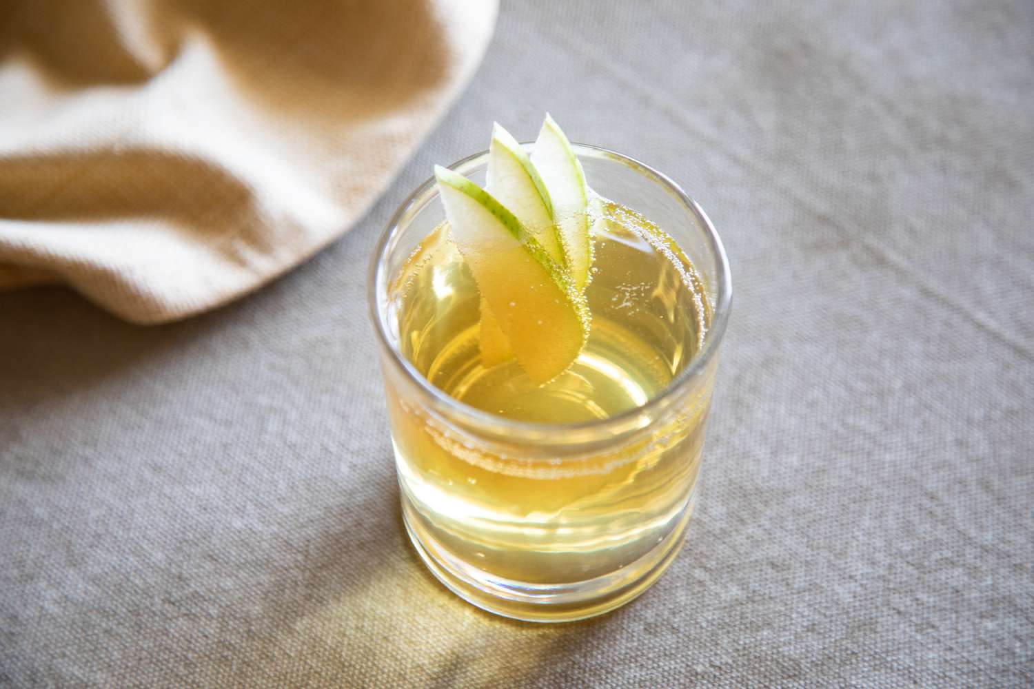 A glass of spiced pear punch garnished with pear slices.