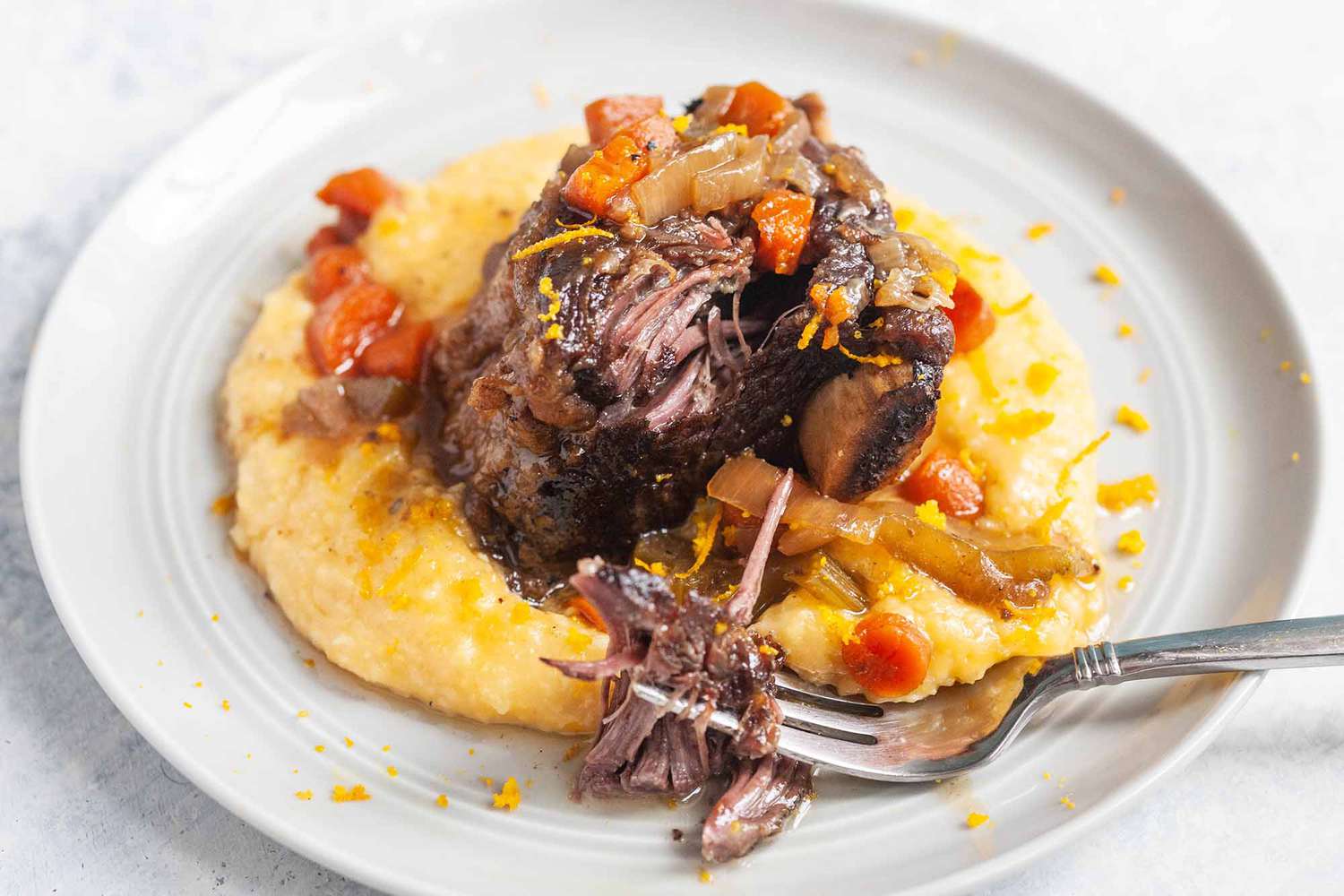 Crockpot Short Ribs on a bed of polenta on a plate
