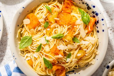 bowl of fresh tomato pasta topped with parmesan shavings and basil leaves (close-up)
