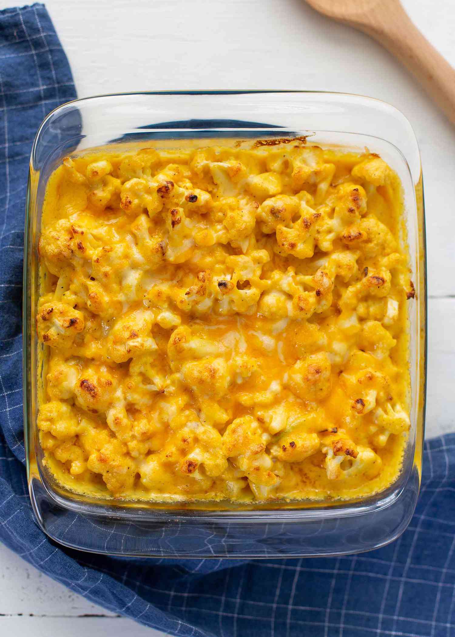 Overhead view of Best Cheesy Cauliflower in a casserole dish with a blue dish towel under it.