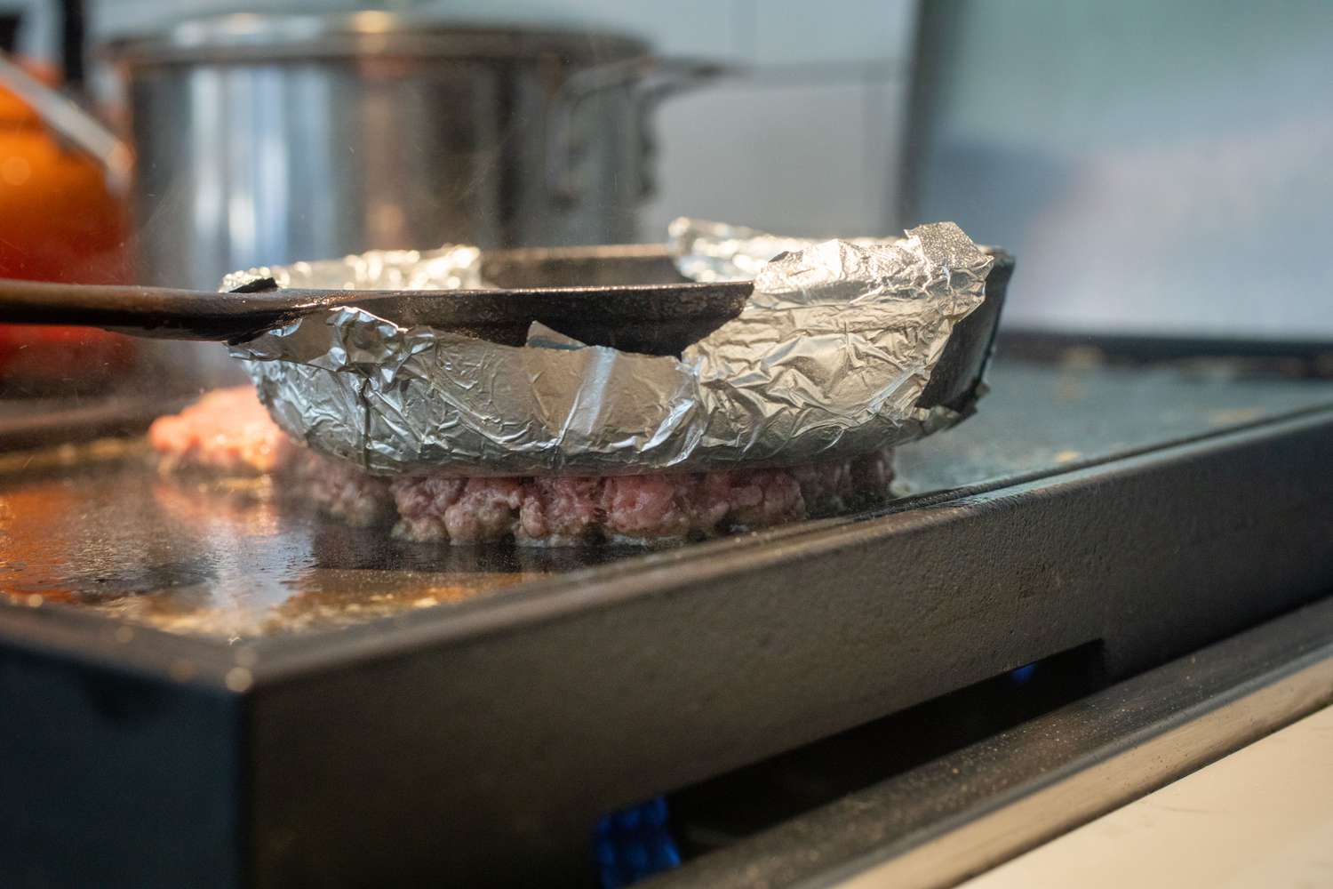 Skillet with foil wrapped around the bottom of it to make a Smashburger-style burger recipe.