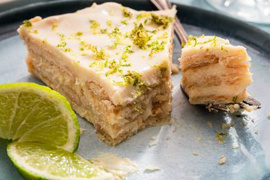Layered dessert served with a fork and garnished with lime slices, focus on texture and freshness