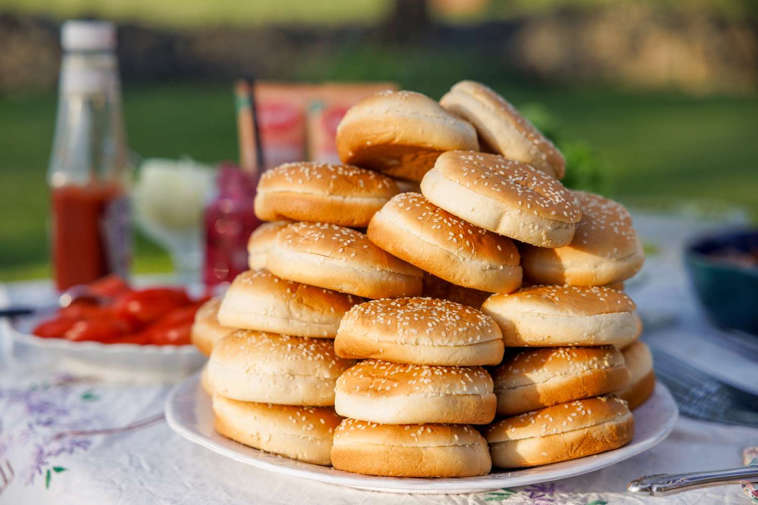 Stack of sesame hamburger buns on a plate outdoors