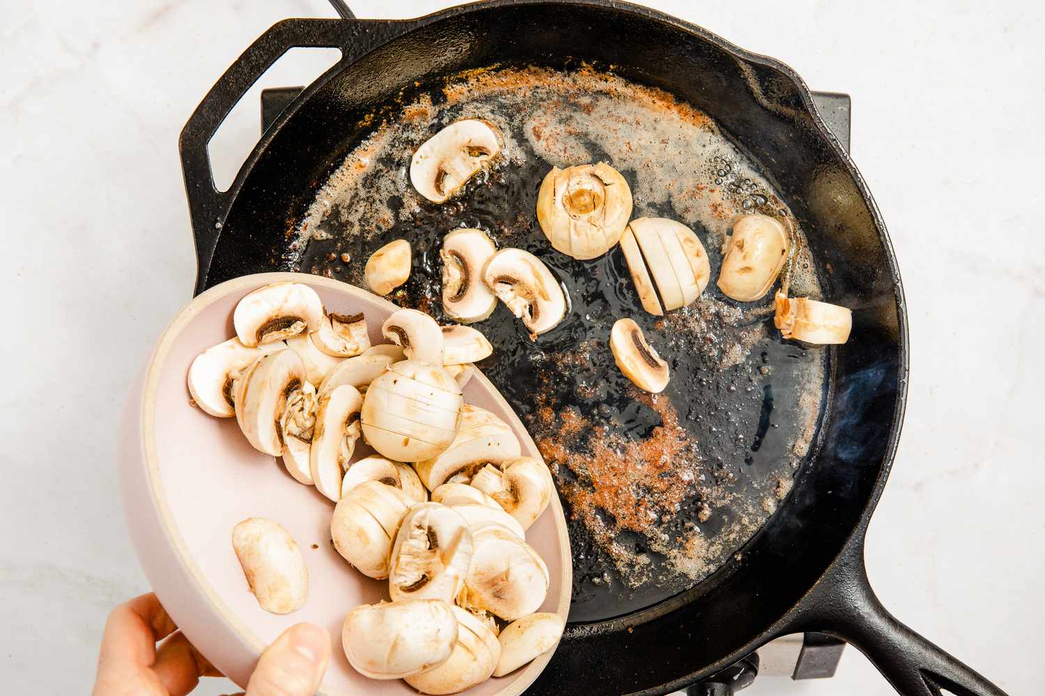 mushrooms added to cast iron skillet for chicken marsala recipe