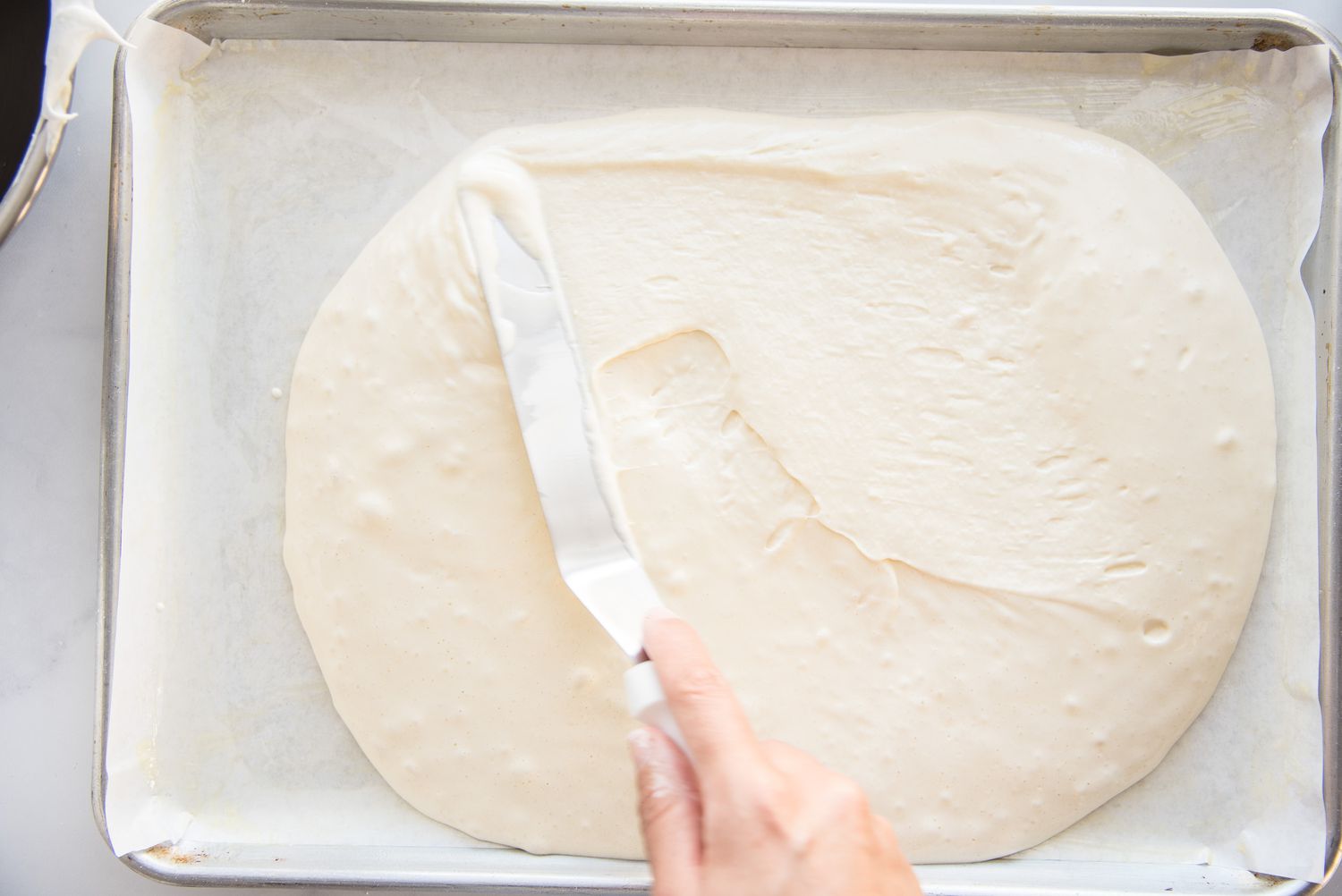 Spreading batter for Brazo Gitano (Spanish Roll Cake) on a sheet pan.