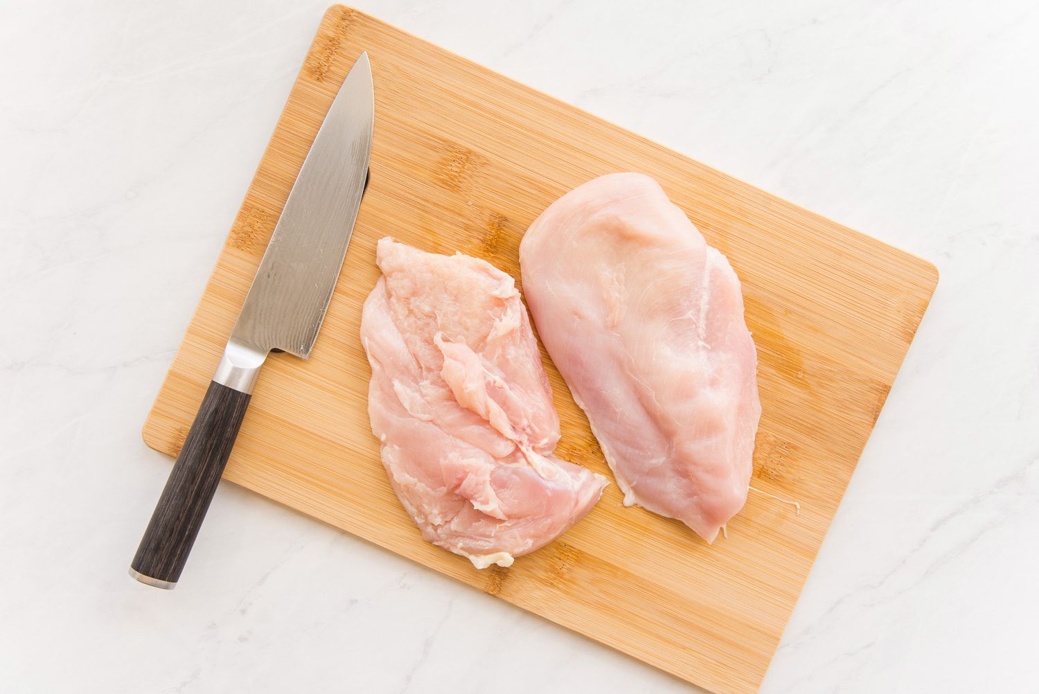 Chicken Breasts Cut in Half on a Cutting Board for Lemon Pepper Chicken Recipe
