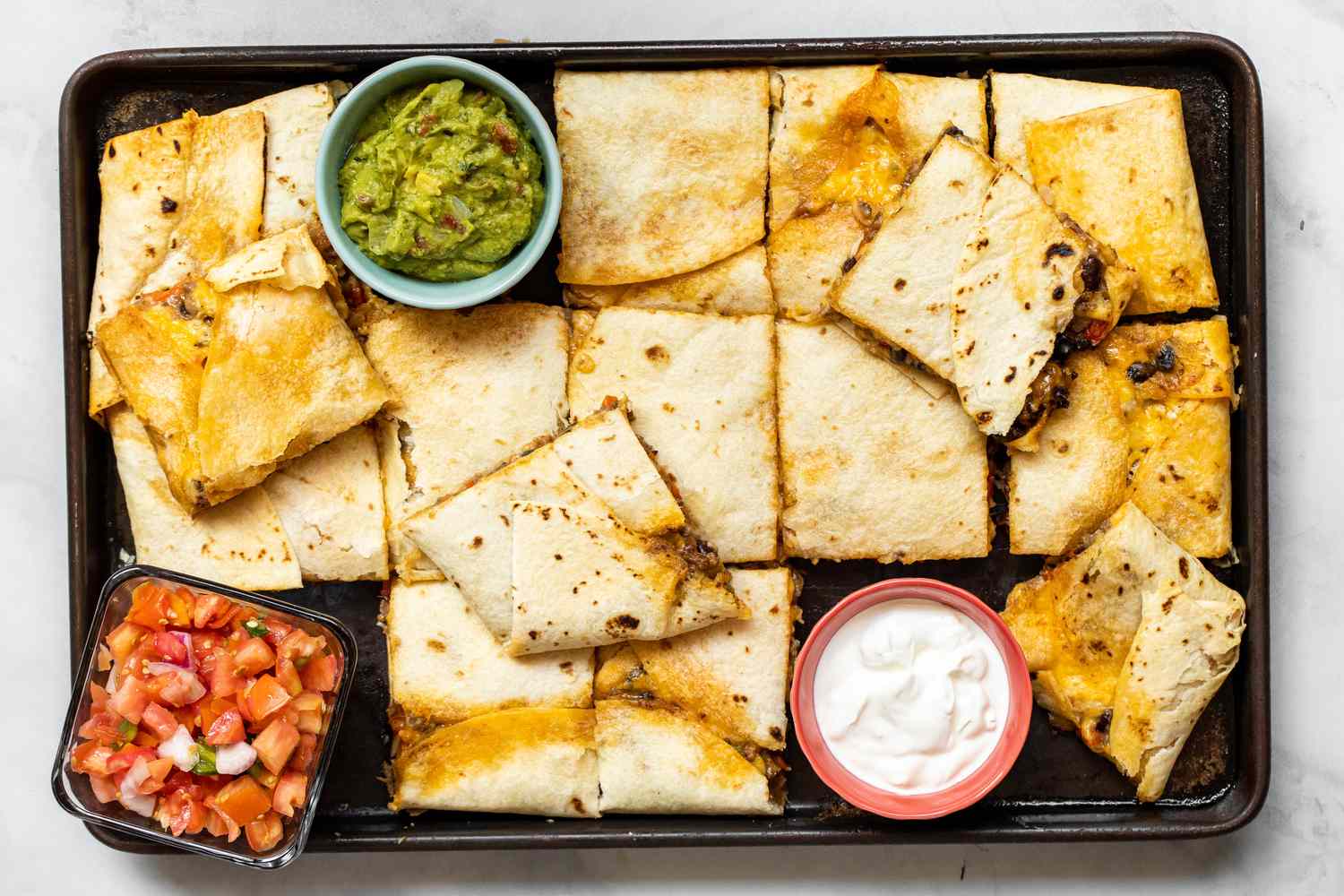 Loaded Sheet Pan Quesadillas with Bowls of Toppings (Salsa, Sour Cream, and Guacamole)