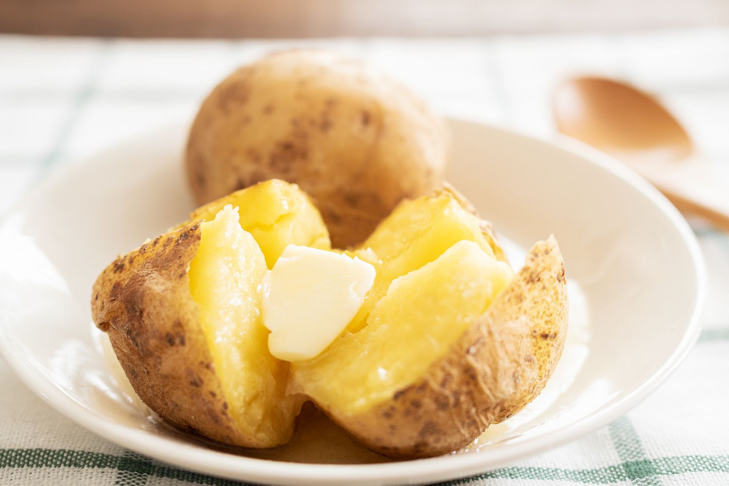 Closeup of split baked potatoes with butter in a white bowl