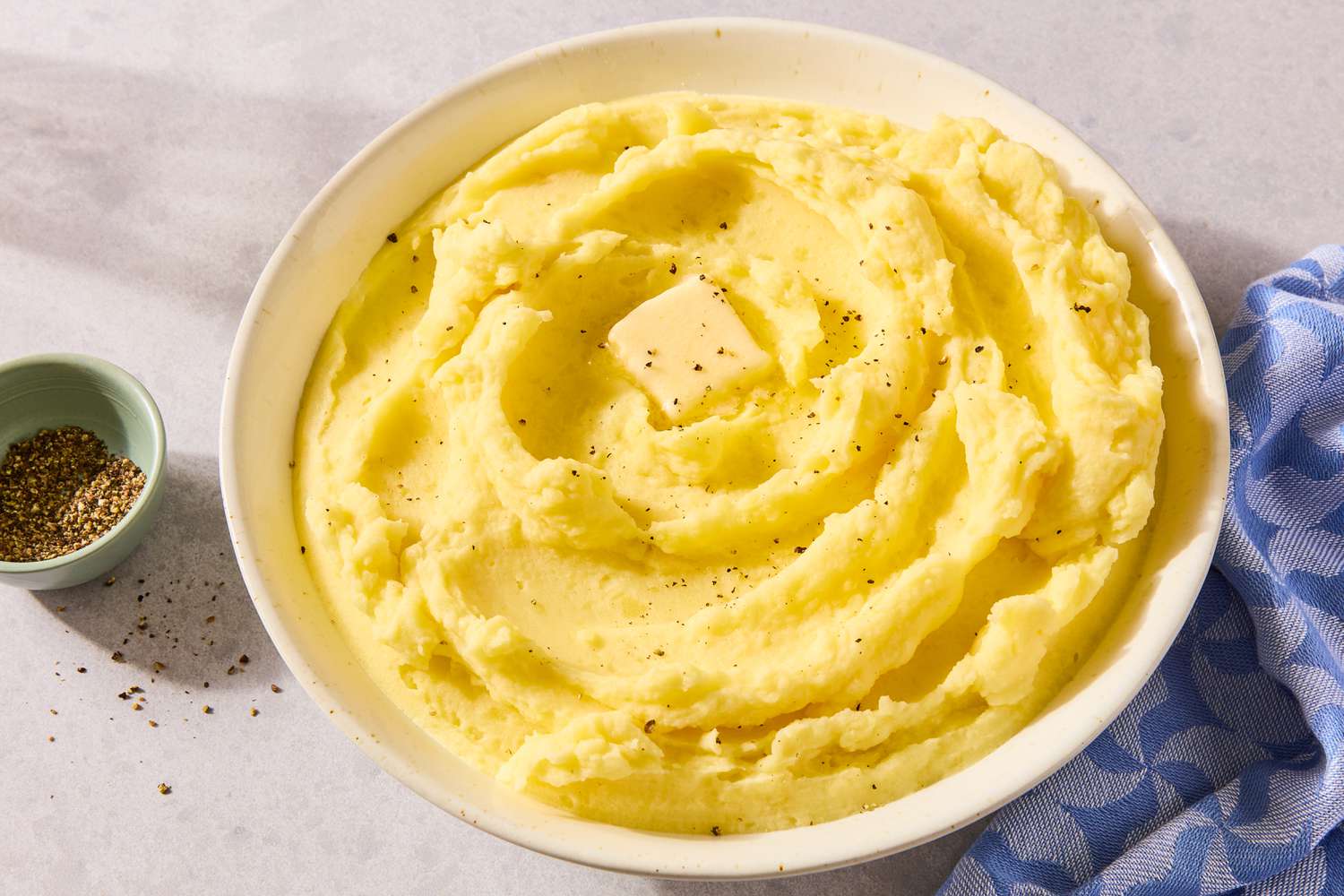 A bowl of creamy mashed potatoes with a butter pat on top