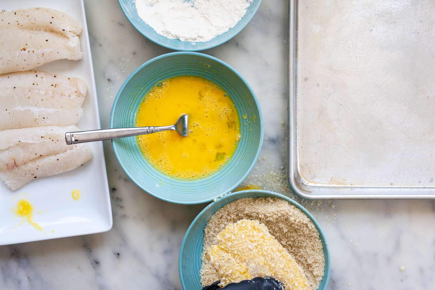 Fish fillet coated in breadcrumbs to make Crispy Oven Baked Fish Sandwiches with Mayo and Tangy Pickled Onions.