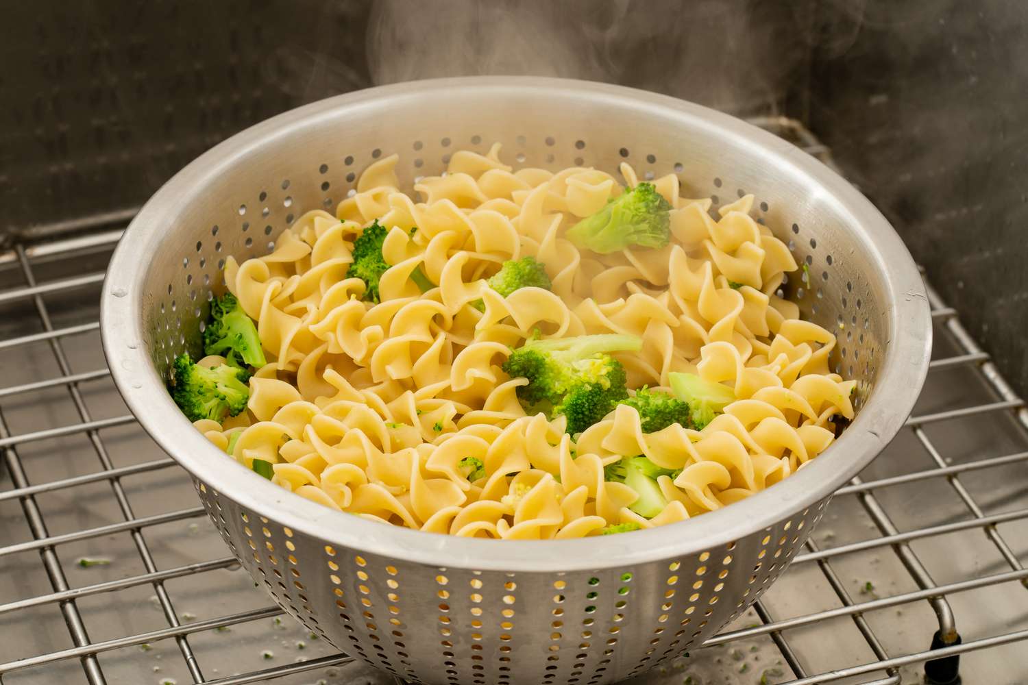 Cooked noodles with broccoli in colander