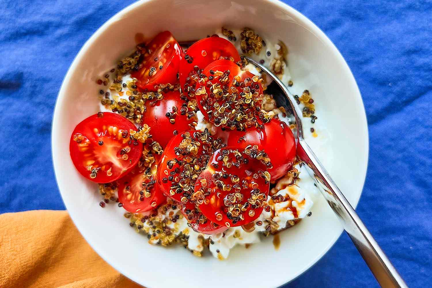 Bowl of tomatoes and cottage cheese topped with Justine Doiron's crispy quinoa