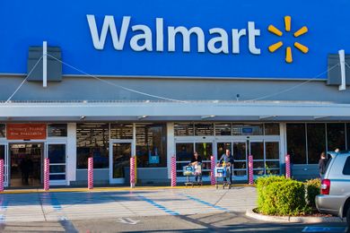 Exterior of a Walmart store with shoppers entering and exiting through sliding doors