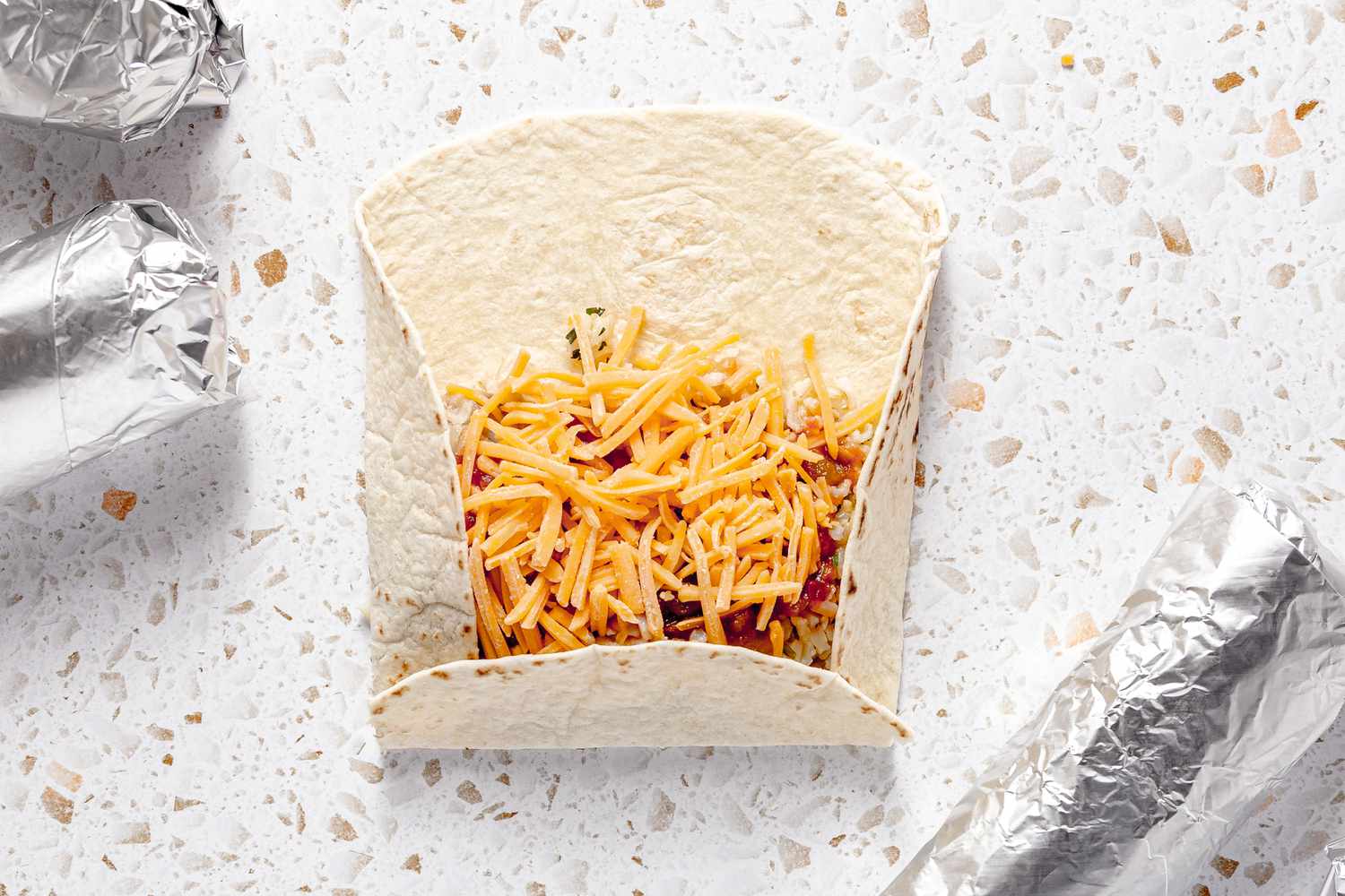 Tortilla Sides and Bottom Folded in Towards the Filling, and in the Surrounds, Easy Rice and Beans Freezer Burritos Wrapped in Aluminum Foil 