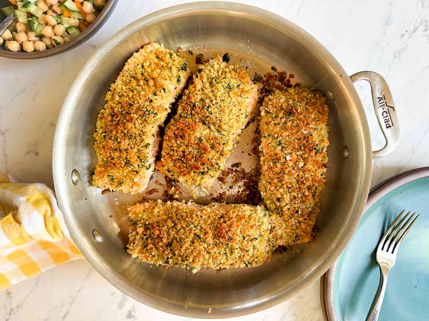 Overhead shot of four breaded salmon fillets getting pan fried