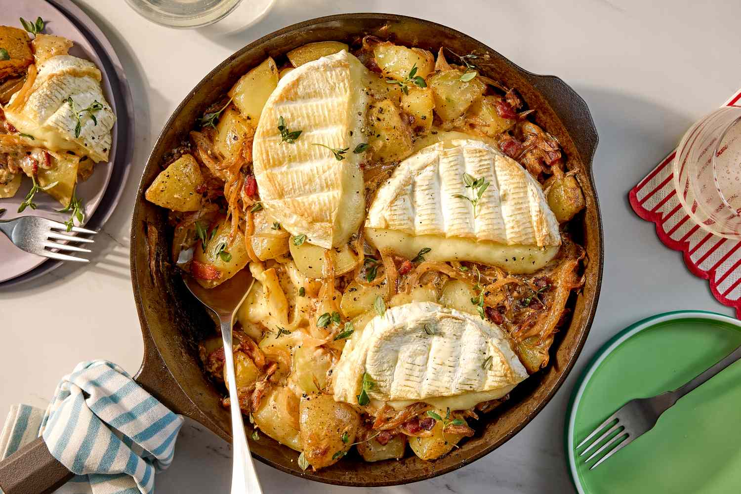 A skillet containing tartiflette a French dish with potatoes and melted cheese