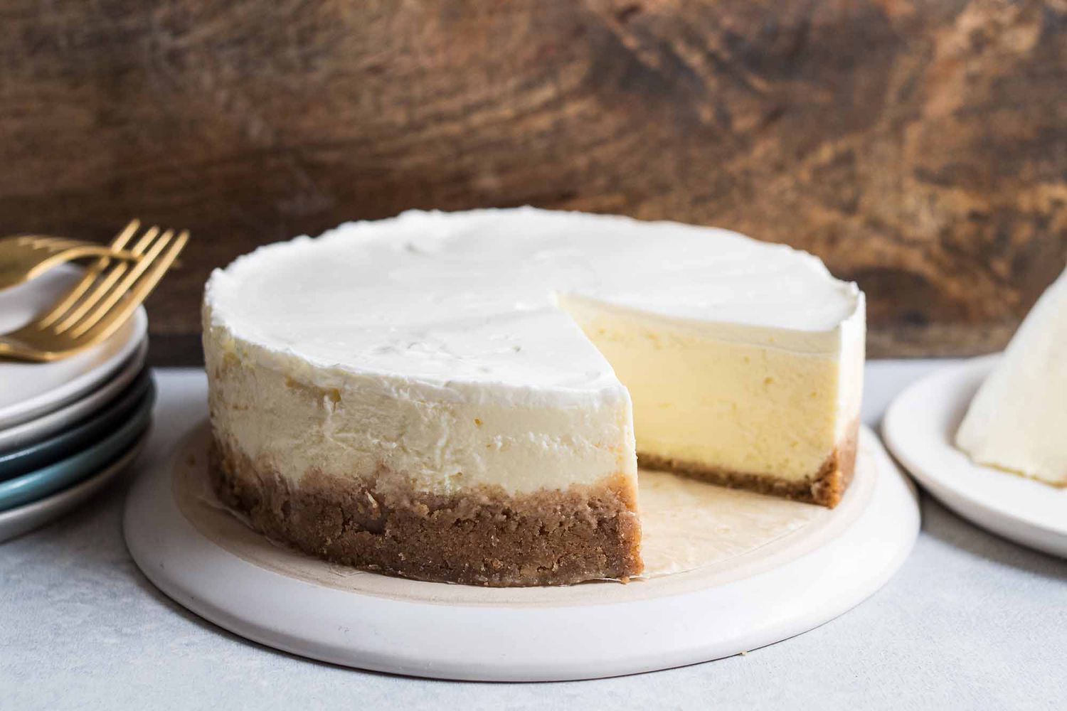 Cheesecake with a slice cut out with plates and forks on the side