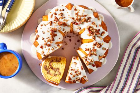 overhead view of Sock It to Me Cake (a bundt cake) on a platter with 2 slices cut out of it, one on its side, napkin, cups of coffee, dessert plate with utensils on the side