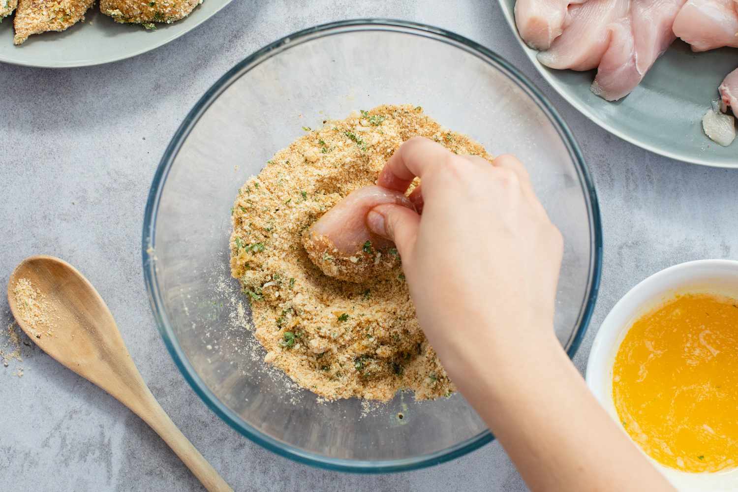 Dipping chicken breast pieces into bread crumbs to make a chicken nuggets recipe.