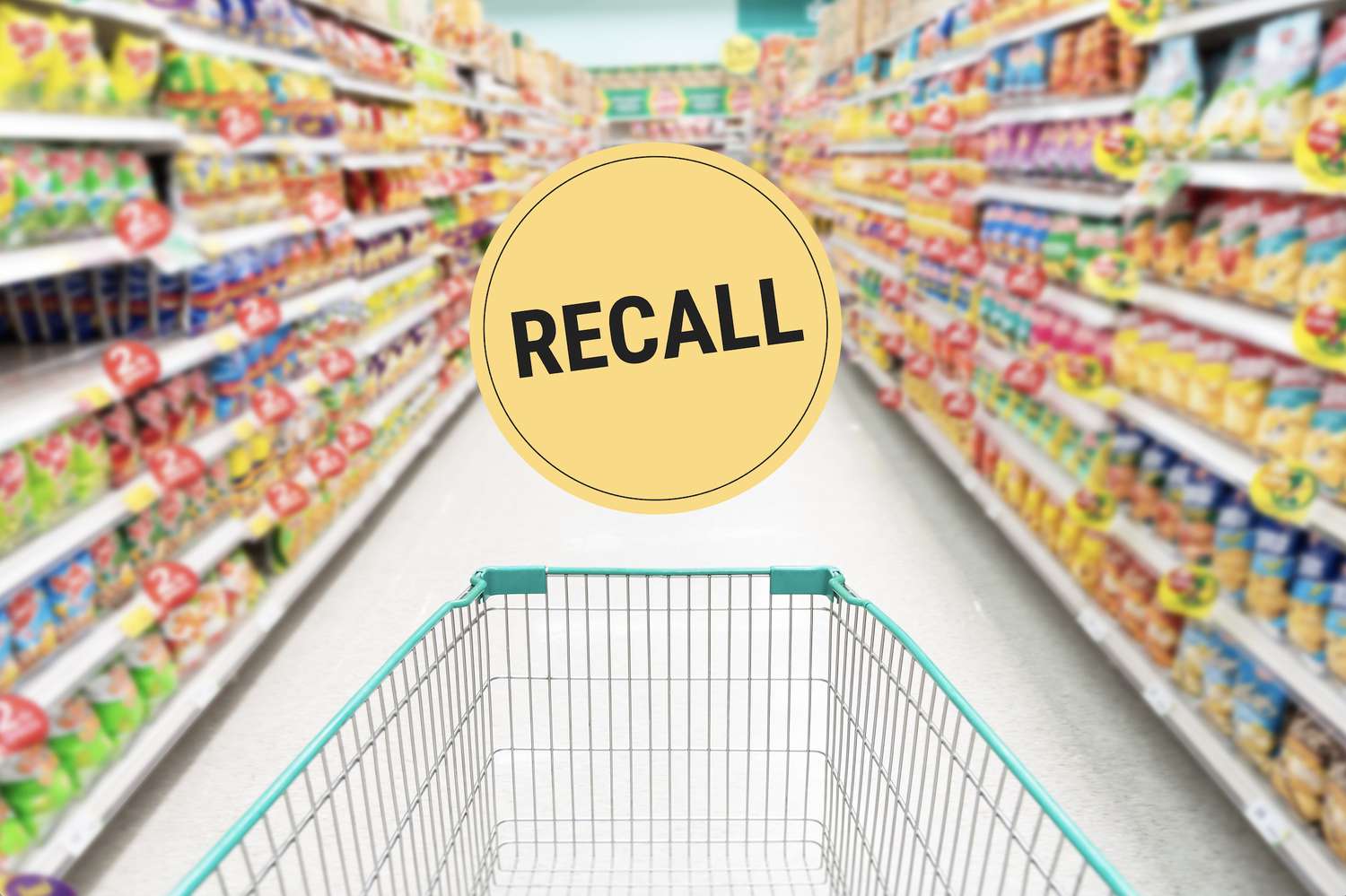 A shopping cart in a supermarket aisle, a circular sign with the word 'Recall' displayed prominently in the center