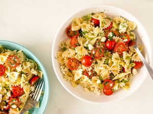 A serving of Greek pasta salad with cherry tomatoes and feta in a white bowl