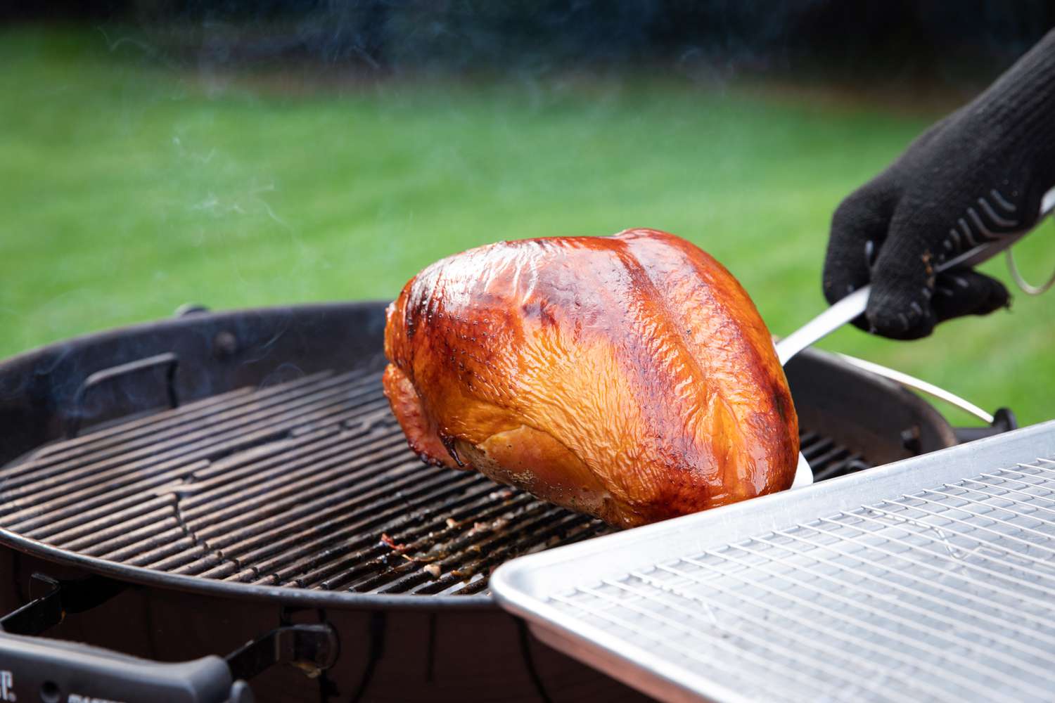 Cherry wood smoked turkey breast being lifted off a grill