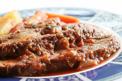 A Swiss steak resting on a blue and white plate 