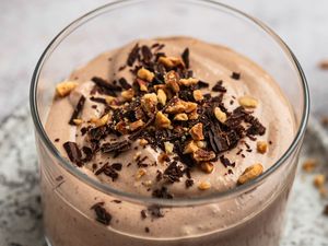 Chocolate yogurt topped with shaved chocolate and nuts in a glass container