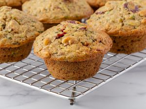 Zucchini muffins with walnuts and cranberries on cooling on a rack.