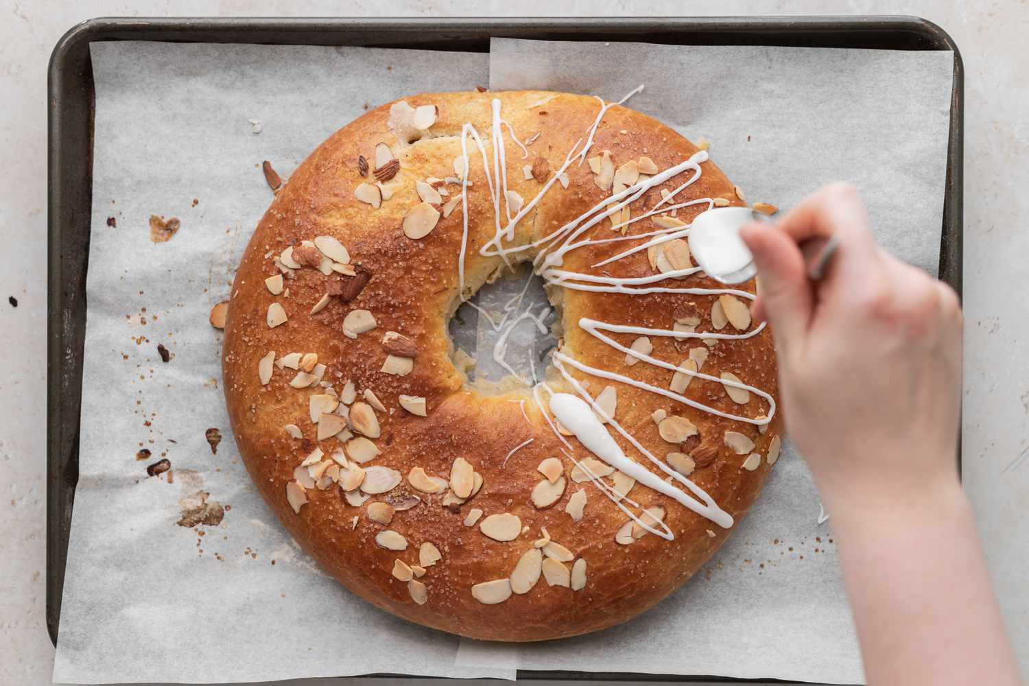 Icing a Danish kringle set on a baking sheet.