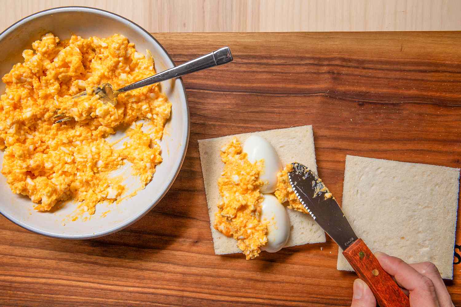 halved eggs added to a slice of bread and topped with more mashed eggs 