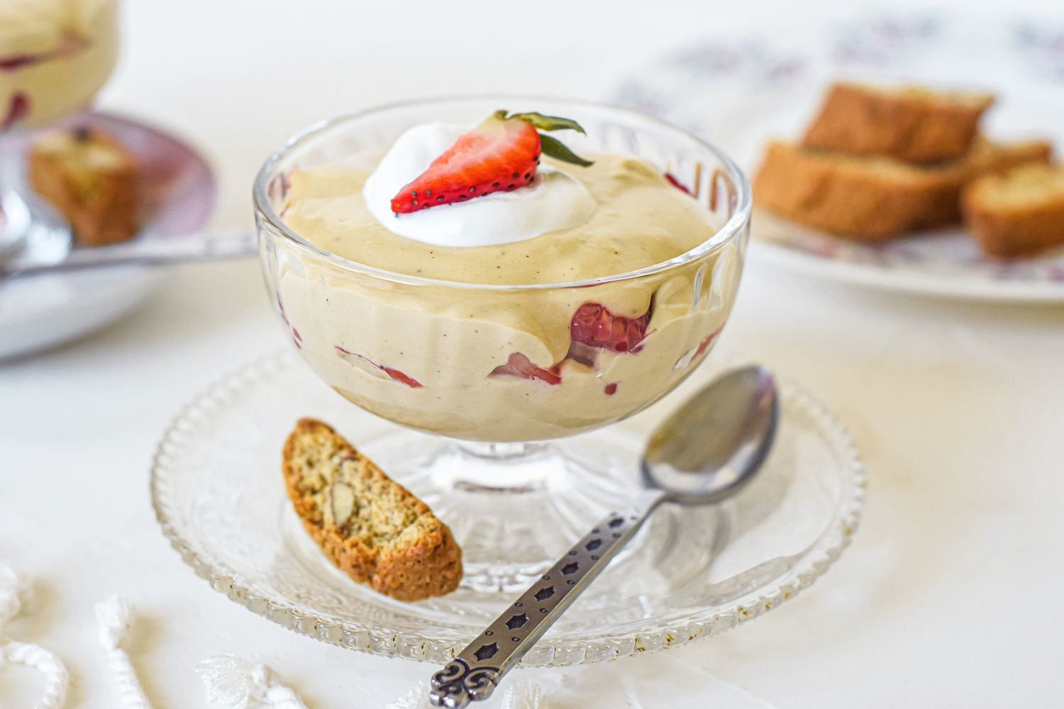 A parfait glass with sabayon sauce topped with cream and a strawberry.