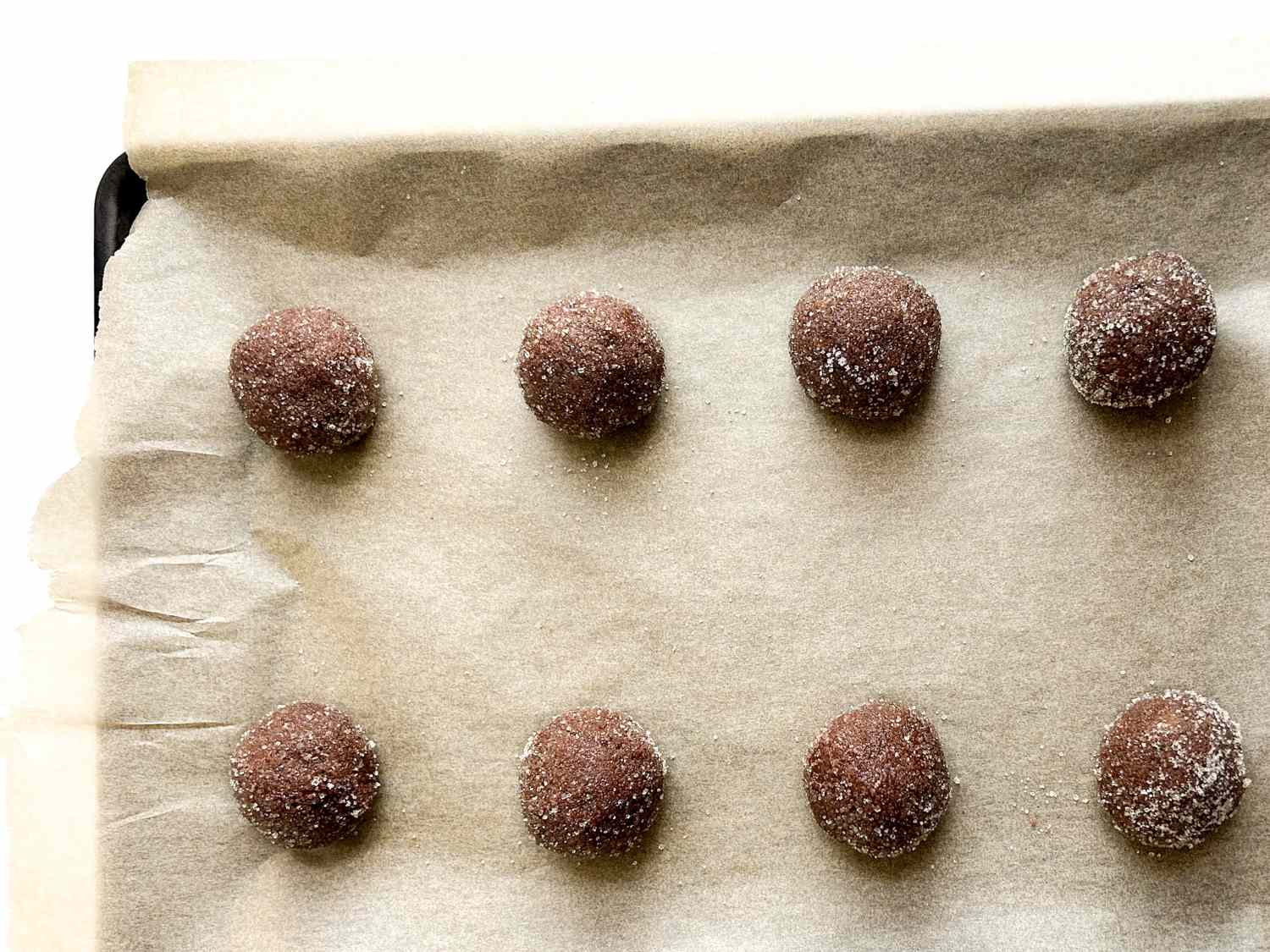 Cookie dough balls placed on a baking tray lined with parchment paper evenly spaced in rows
