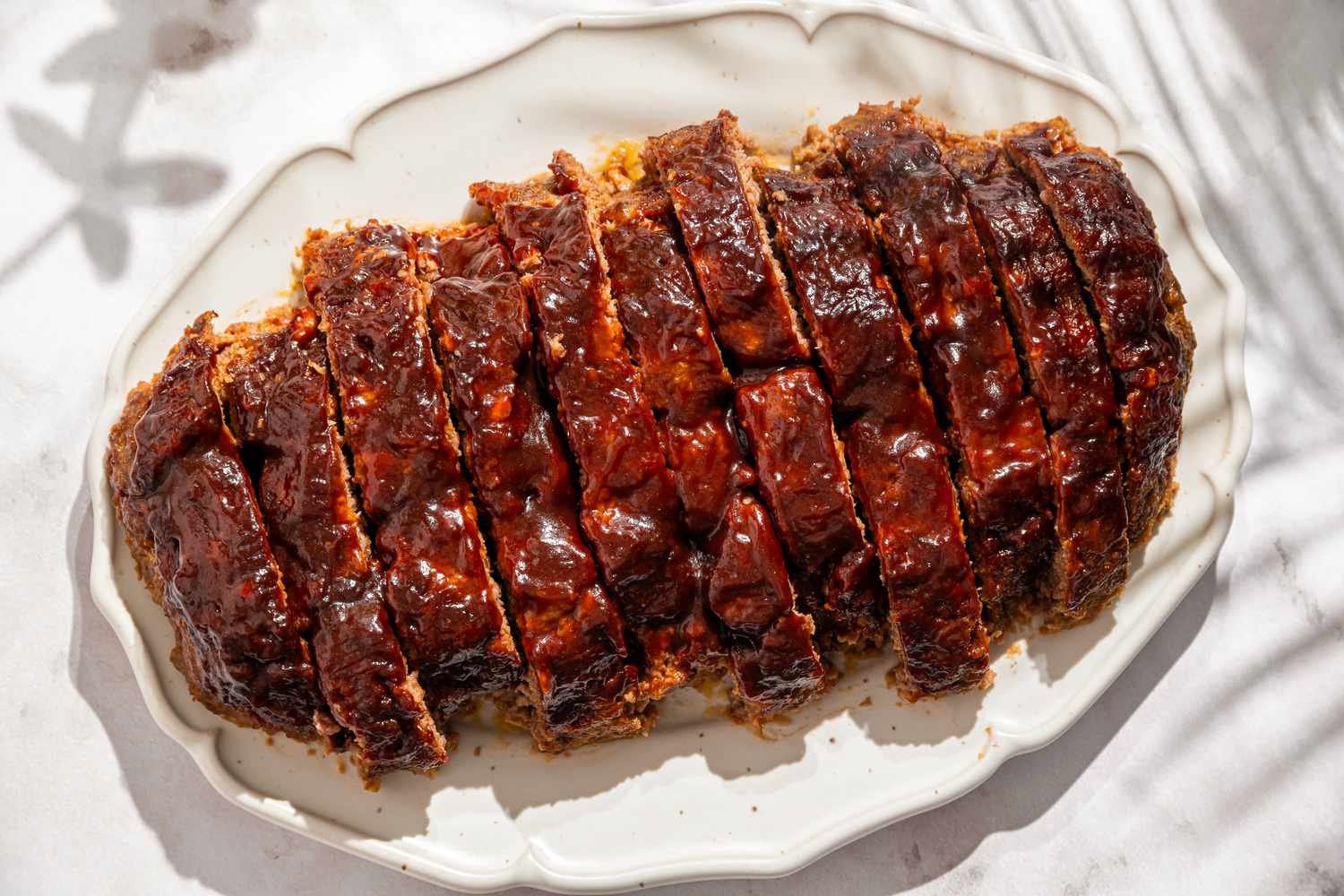 Overhead shot of a sliced up 5-ingredient meatloaf on a white serving plate
