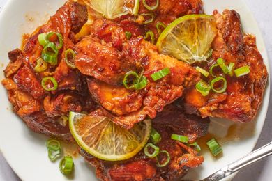 Plate of glazed chicken pieces garnished with lemon slices and green onions