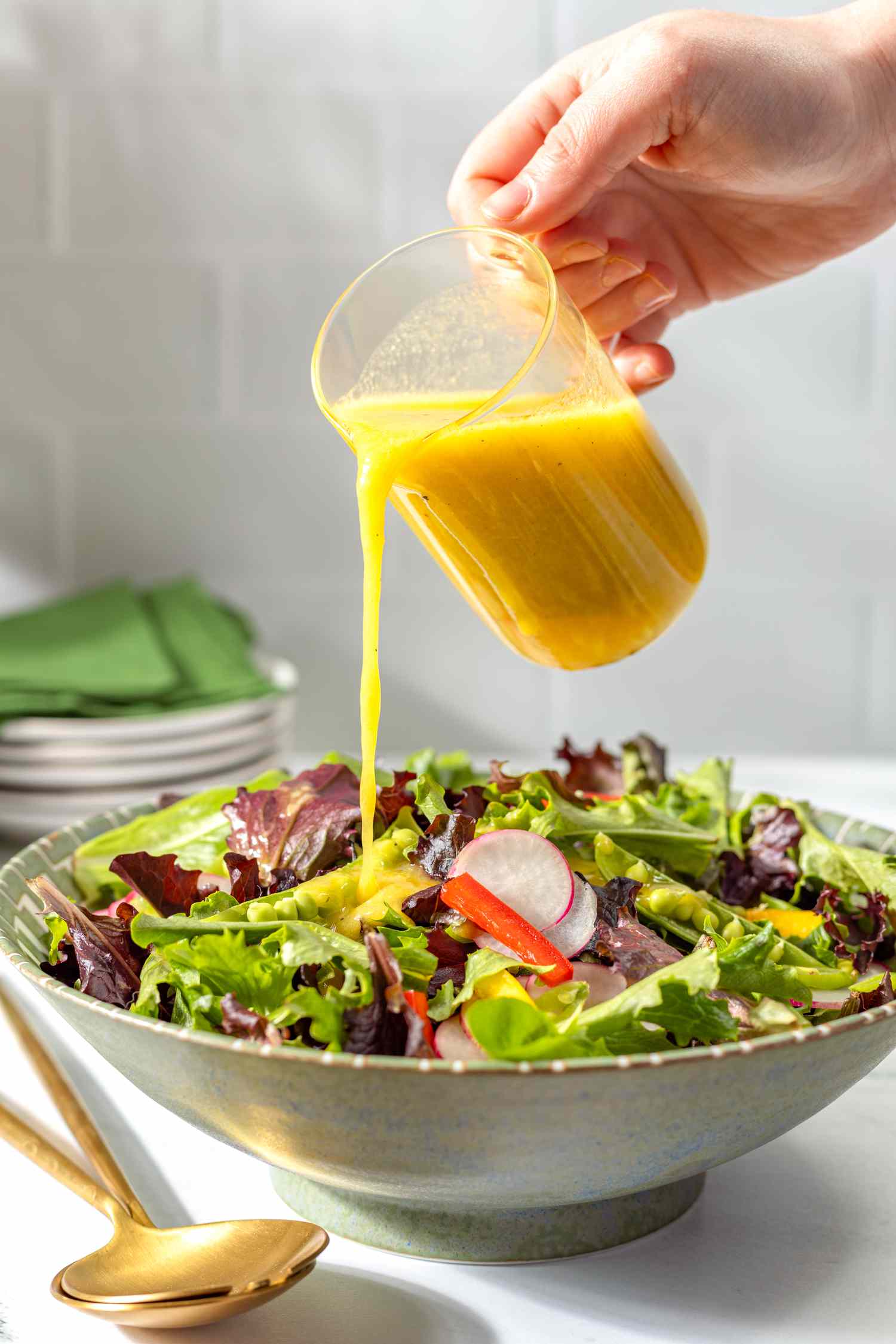 ginger dressing poured onto a mixed green salad