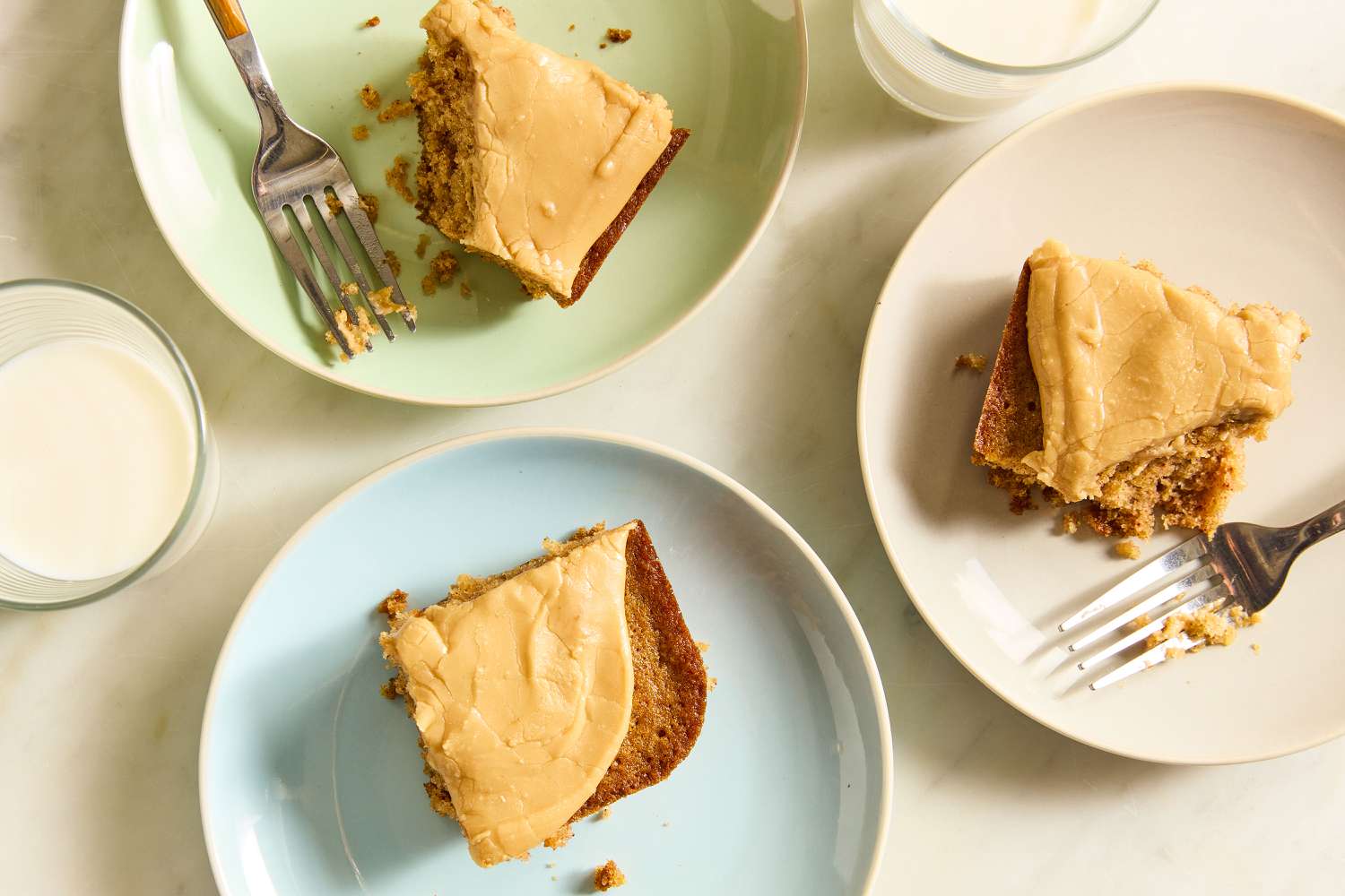 slices of Grandma’s Oatmeal Cake on dessert plates with forks and glasses of milk