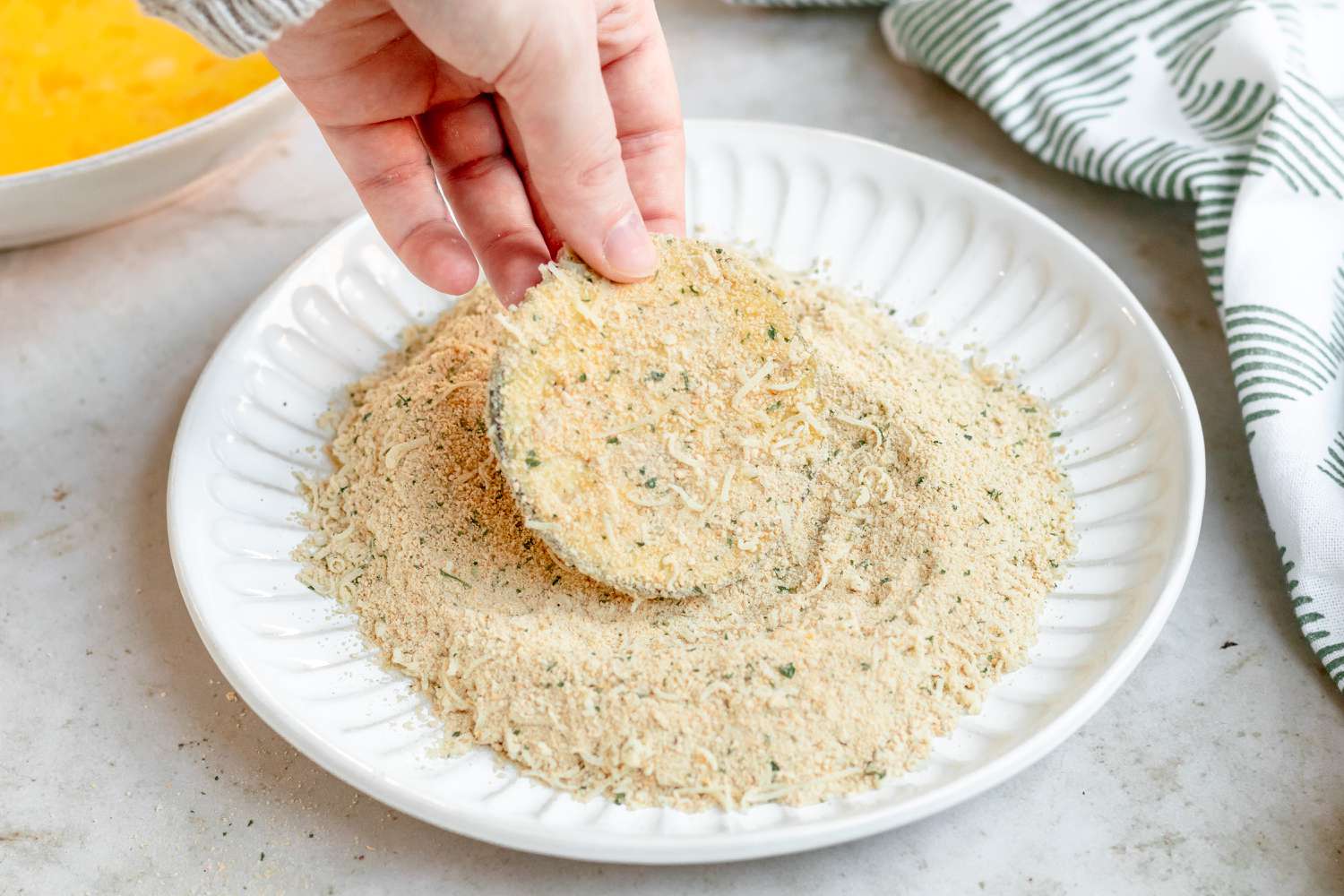 Dipping a sliced egg plant in breadcrumbs