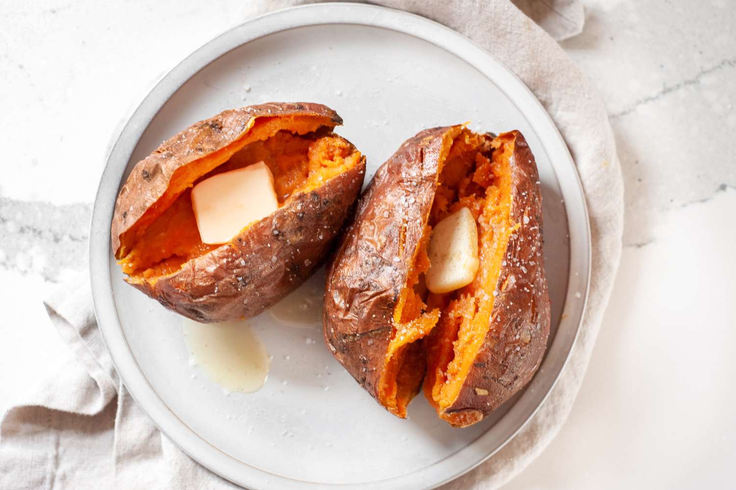Plate with Microwave Sweet Potatoes Split in Half and Topped with a Slab of Butter and Salt 