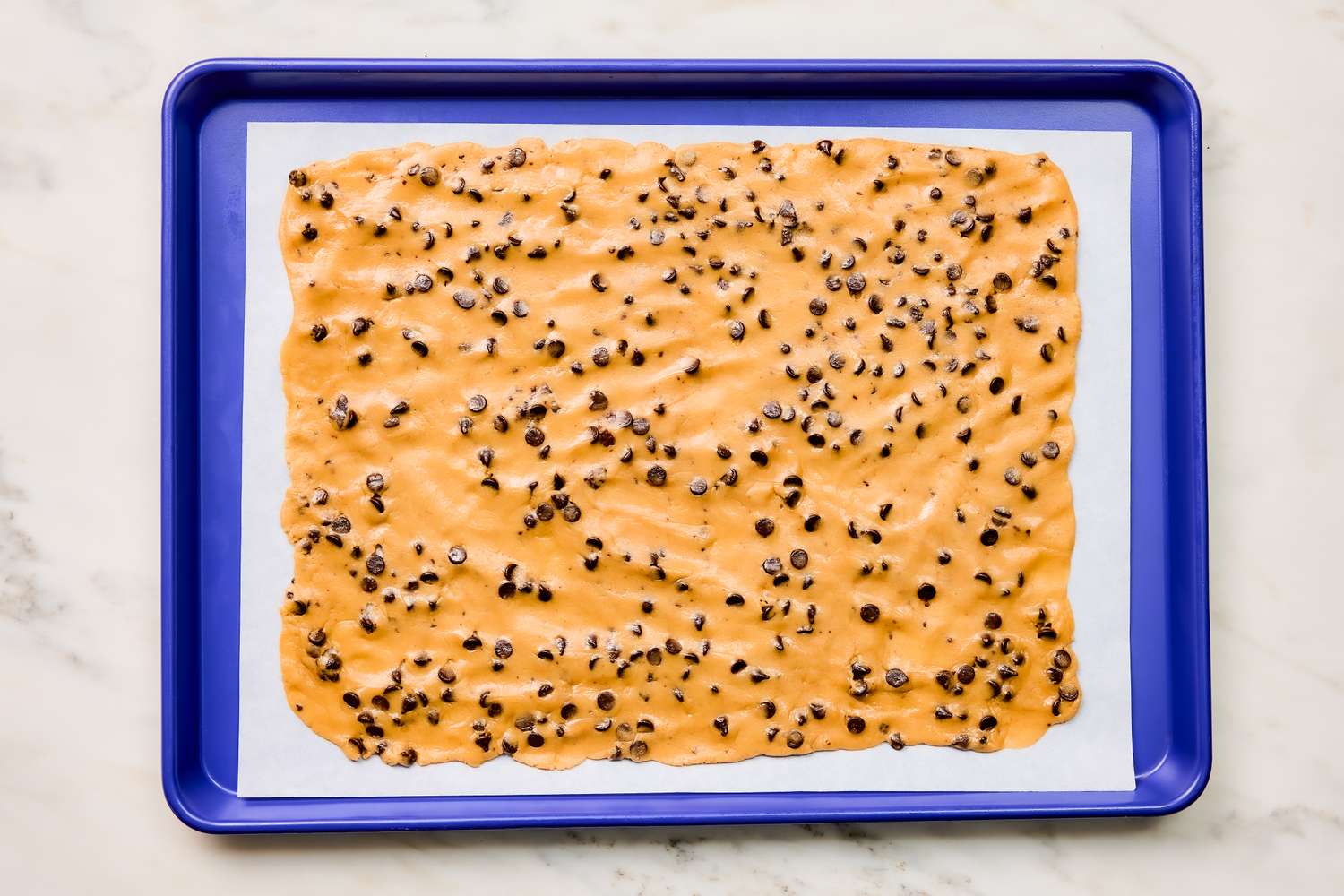 cookie dough pressed flat out on a parchment lined baking pan