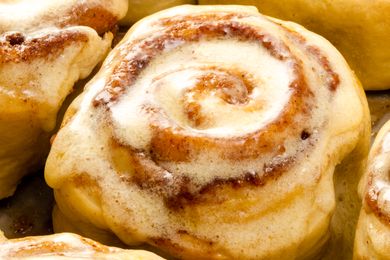 A closeup of a glazed cinnamon roll with visible swirls of cinnamon filling and icing