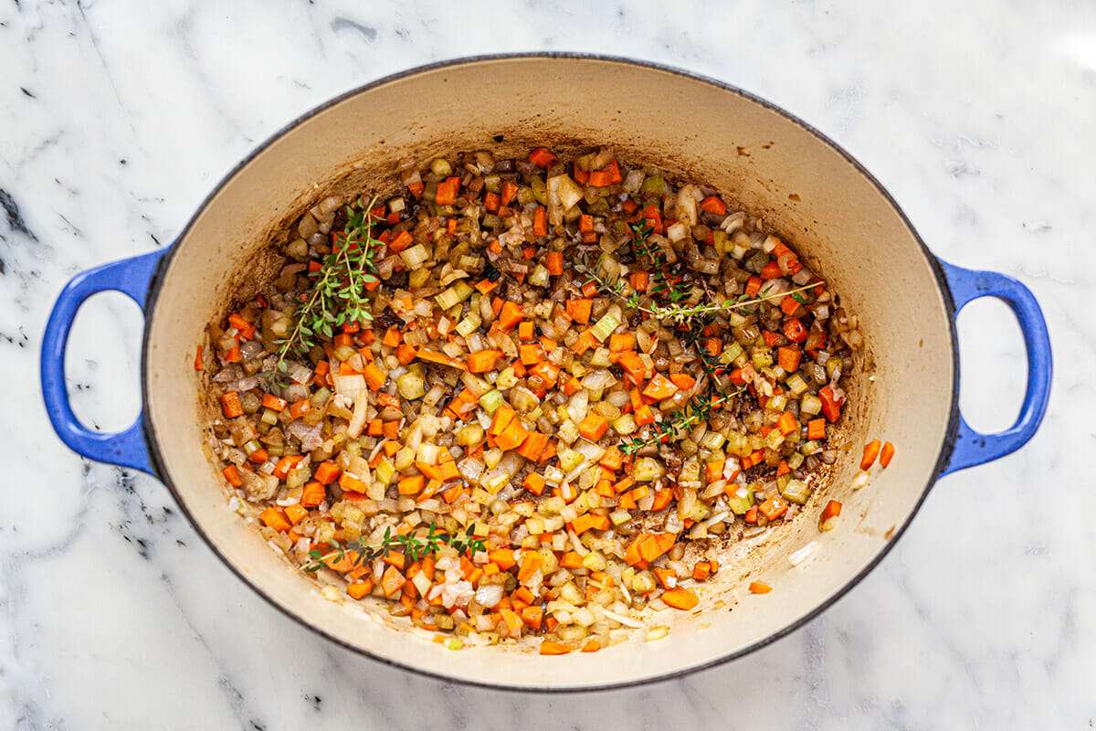 A blue dutch oven with osso bucco inside.