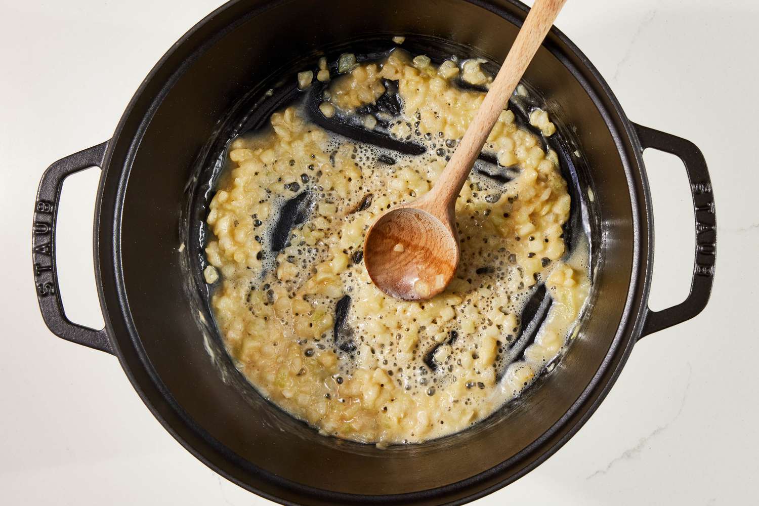 Flour, butter, and onions stirred together to create a roux in the Dutch oven for Diced onion cooking in a Dutch oven for copycat Panera broccoli cheddar soup recipe