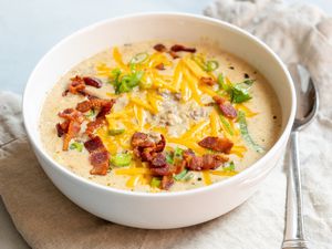 Cheesy bacon cheeseburger soup in soup bowl and with spoon.