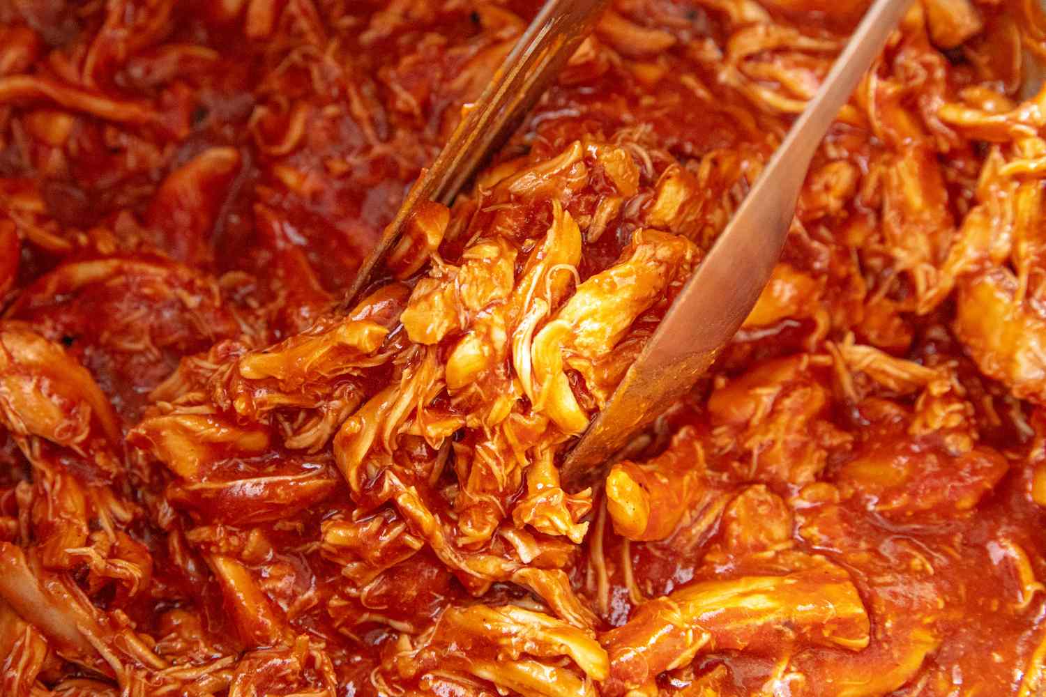 Shredded barbecue chicken being served with tongs